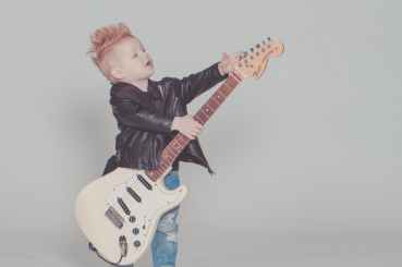 boy wearing black jacket holding electric guitar